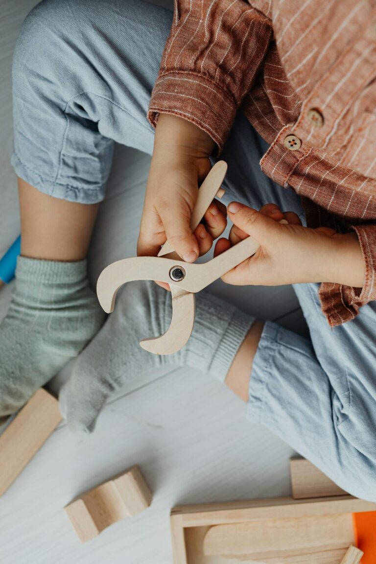 A child sitting cross-legged, playing with a wooden plier toy, showcasing creative play.