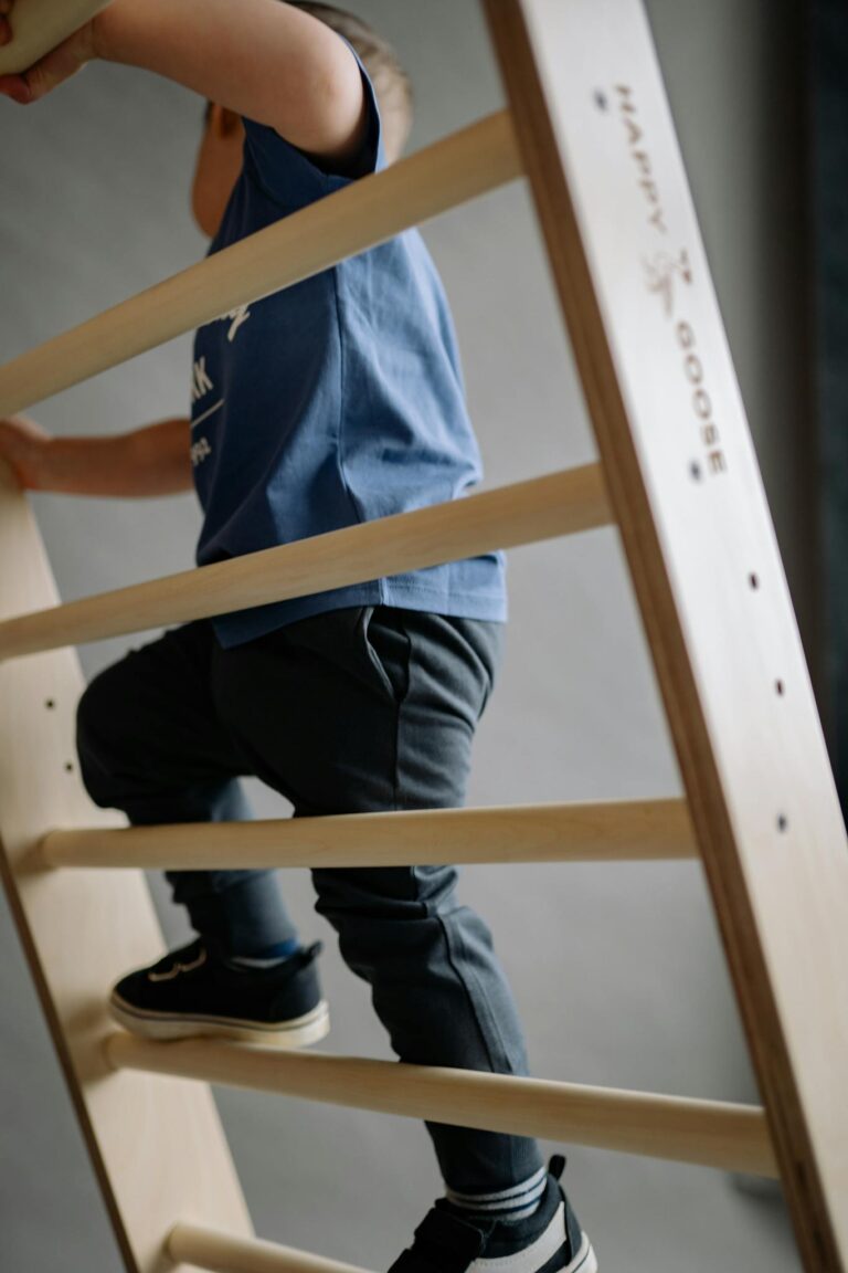 A young child climbing an indoor wooden climbing frame, showcasing play and activity.